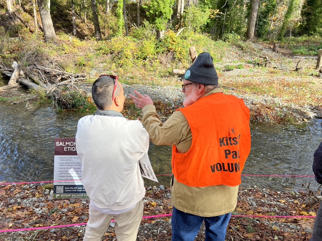 Photo of Salmon Docent talking to the public, pointing out the salmon migrating up to spawning grounds at Chico Salmon Viewing Park for Salmon Tours event