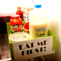 Image of box with sign saying "Eat me First" located in the refrigerator.