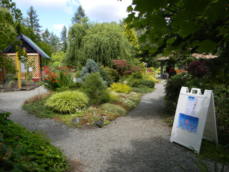 Gardens and pathways at Dirt Works Demonstration Garden leading to Gazebo with people inside.