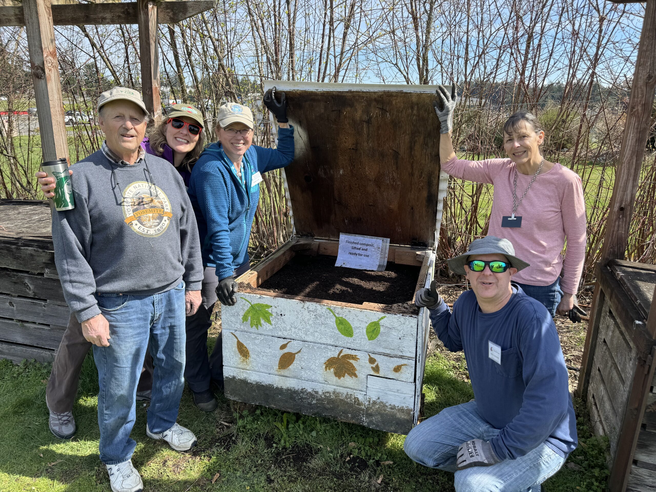 Volunteers posing around a wood compost bin