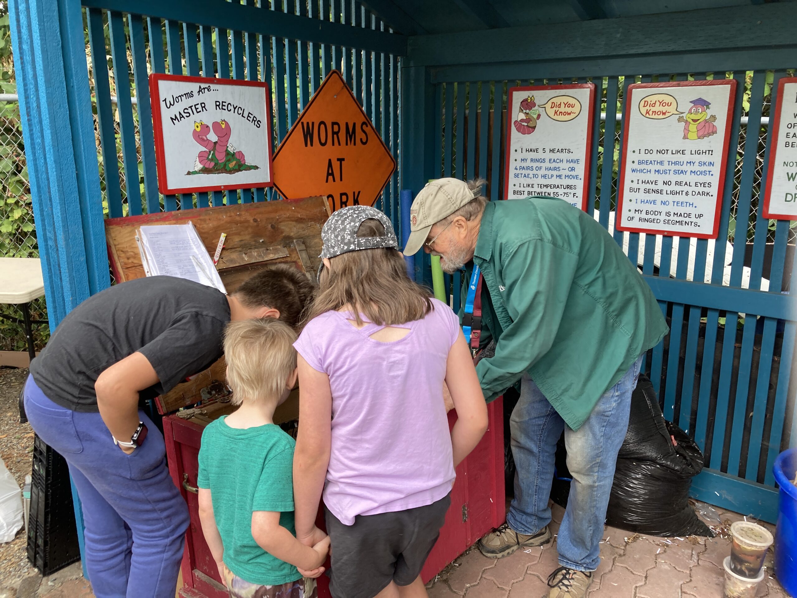 Master Recycler Composter volunteer showing children's garden participants the worm bin at Dirt Works.