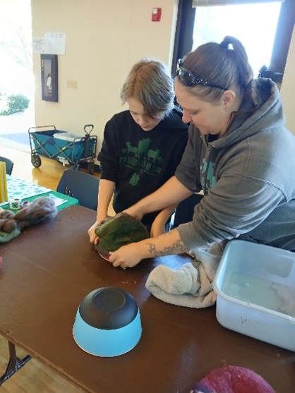 4-H volunteer helping a youth wet felt a wool hat