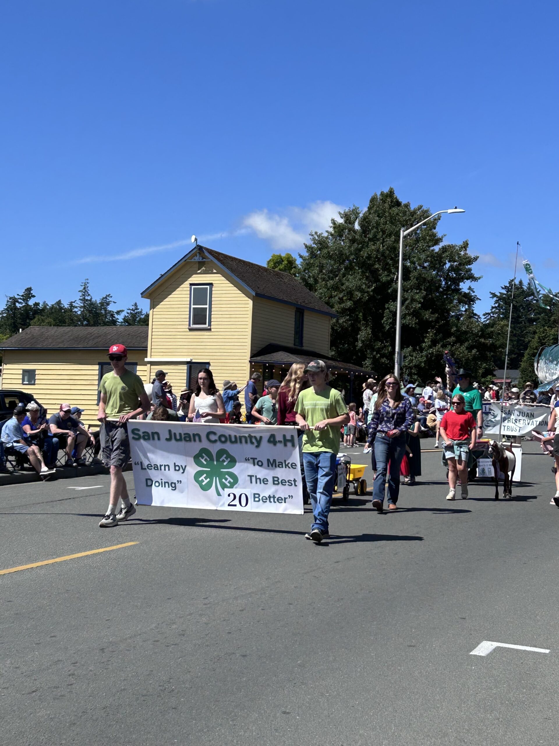 People marching in a 4th of July parade holding a San Juan County 4-H banner.