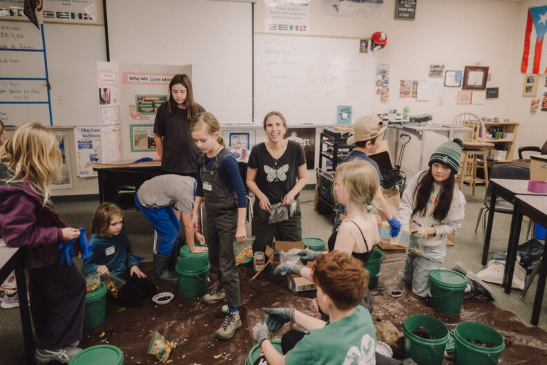 Youth and a 4-H volunteer working together on a hands-on worm bin activity.