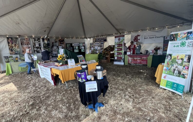 Image of displays at the Agriculture Tent at the San Juan County Fair- showing colorful farm photos, Ag Organization banners and displays