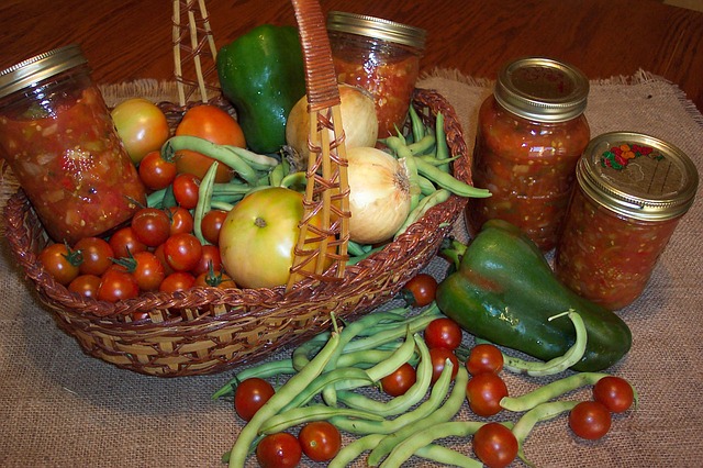 Basket with produce harvested for salsa ingredients and jars of preserved salsa