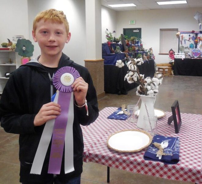Connor S. holds Grand Champion ribbon inside the 4-H building at fair.