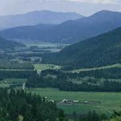 Aerial photo of Stevens Valley in the summer. The valley is lush and green and the layers of mountains are shades of blue fading into the distance.