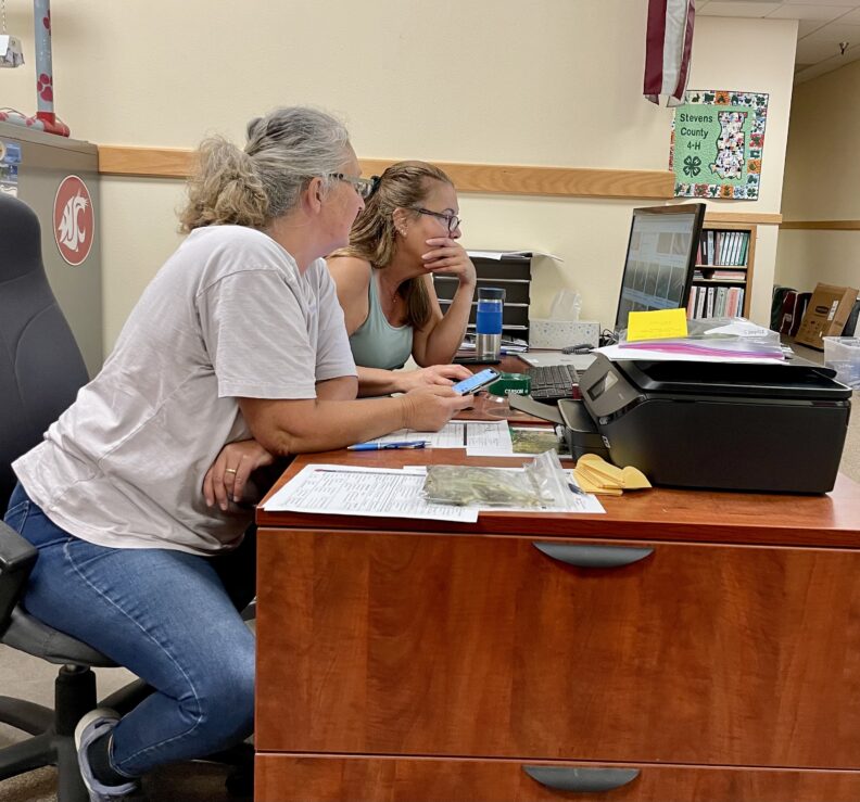 2 Master Gardeners looking at a computer screen, researching a problem sent to the Answer/Plant Clinic.