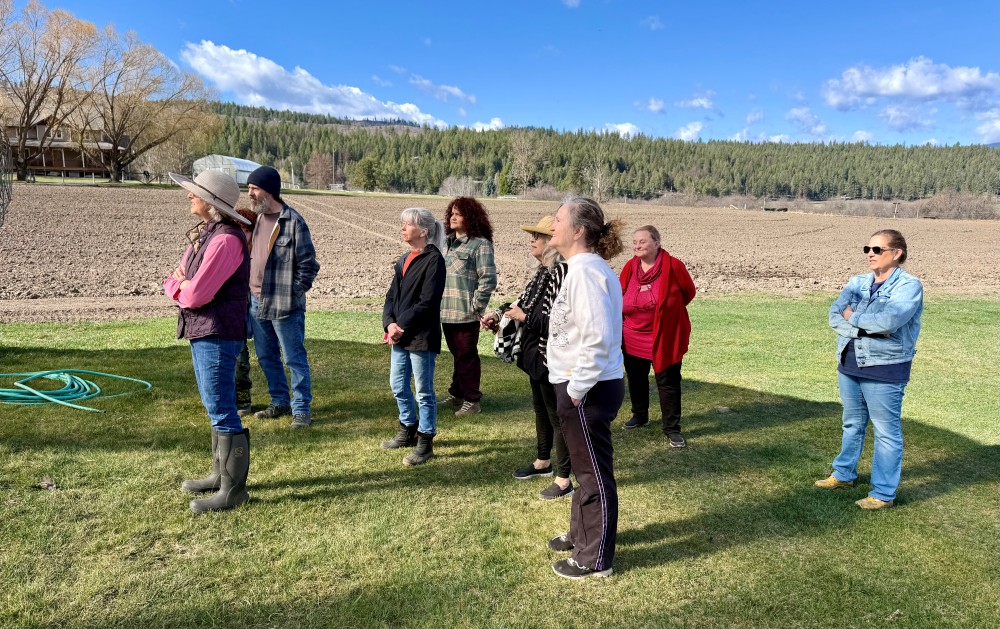 "Close Encounters of the Plant Kind". The 2025-2026 Master Gardener class of students stand facing toward the sunlight as they listen to trainings from the owners at Front Porch Farm.