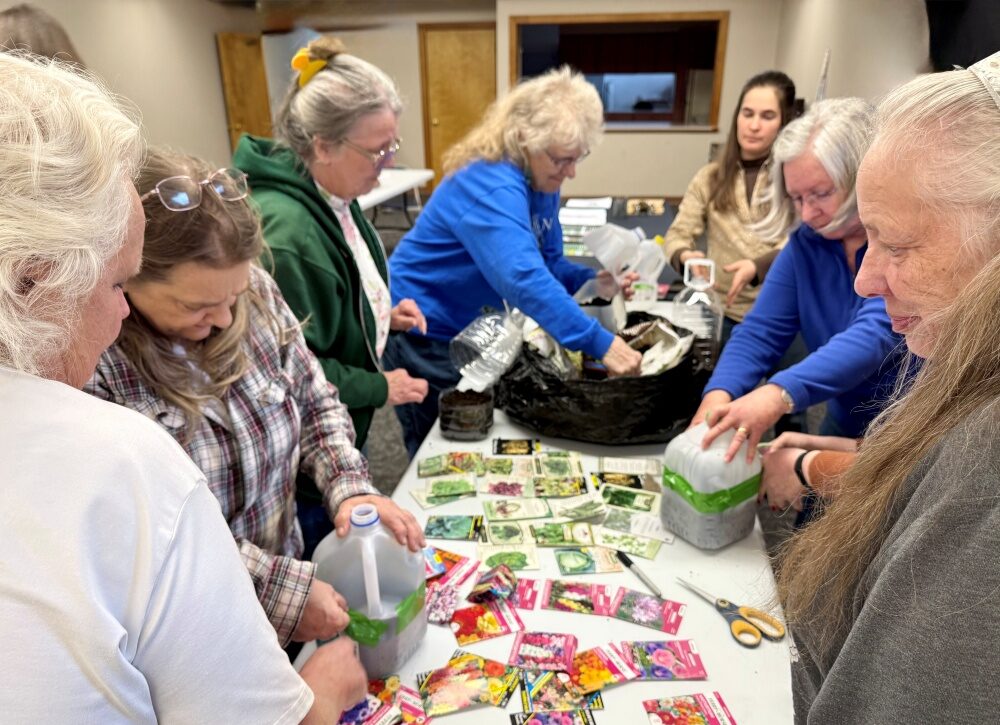 Master Gardeners Elisabeth and Jackie helping Winter Sowing class attendees to complete their milk jug greenhouses