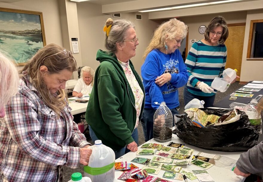 Winter Sowing library class attendees gather around a table to choose seeds to plant in their Milk Jug greenhouses.