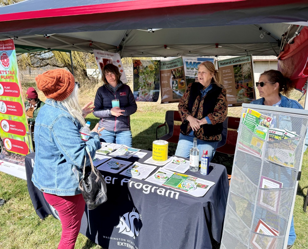 Master Gardeners Sandy and Kim with MG Intern Chris (right) conversing with a customer at the Conservation District Tree Sale booth.