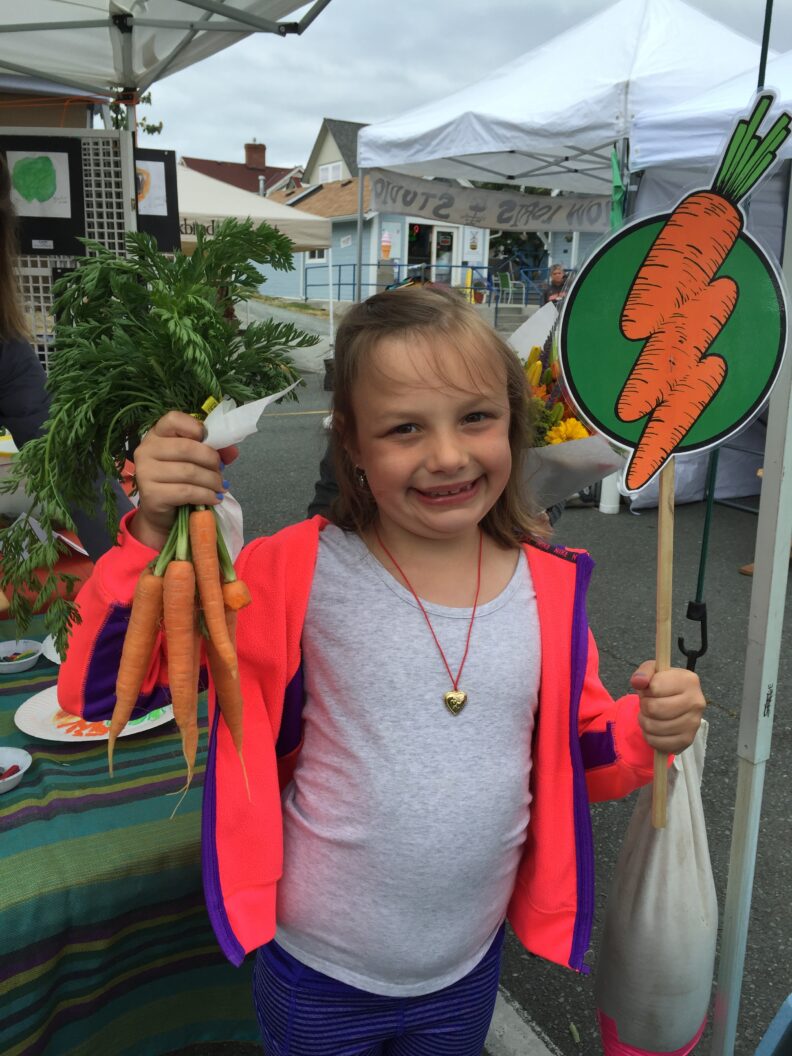 A young gardener showing off her harvest.