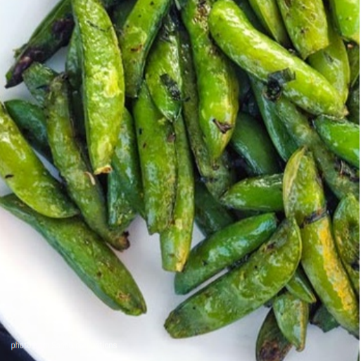 Roasted snap peas on a white plate.