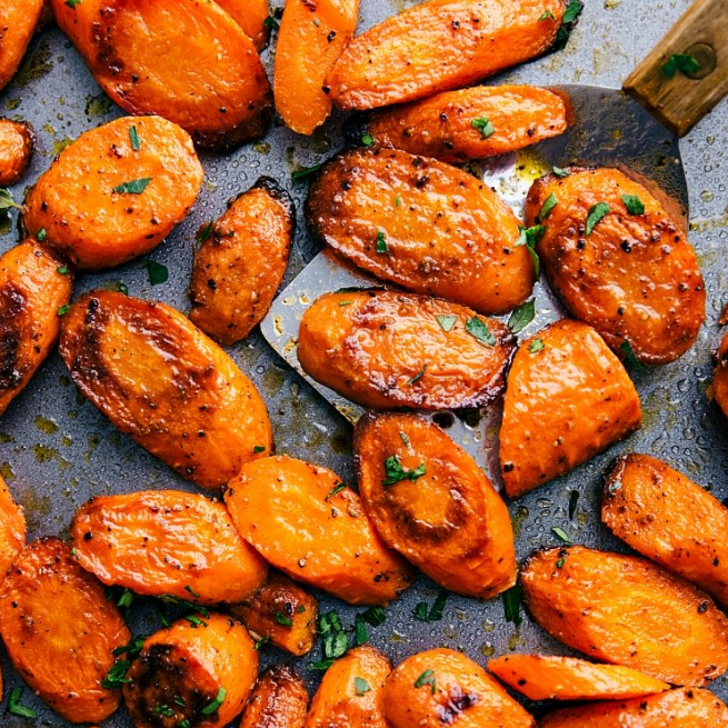 Glazed baked carrots on a baking sheer with a metal spatula underneath