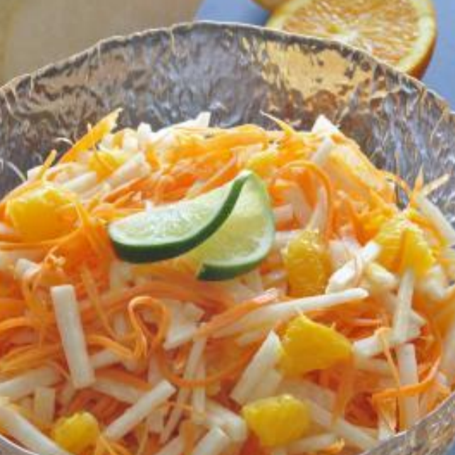 A bowl of jicama and carrots with a lime wedge on top