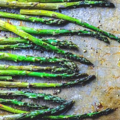 Roasted asparagus with oil and salt on a baking sheet. 