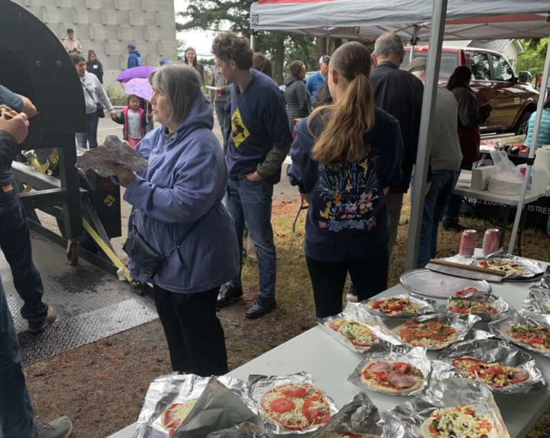 WSU Skagit Extension and Pizza For Producer Volunteers prepare pizzas to be baked in the wood fired pizza oven