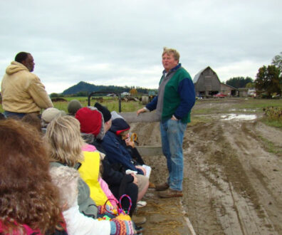 students listen to organic farmer in farm field