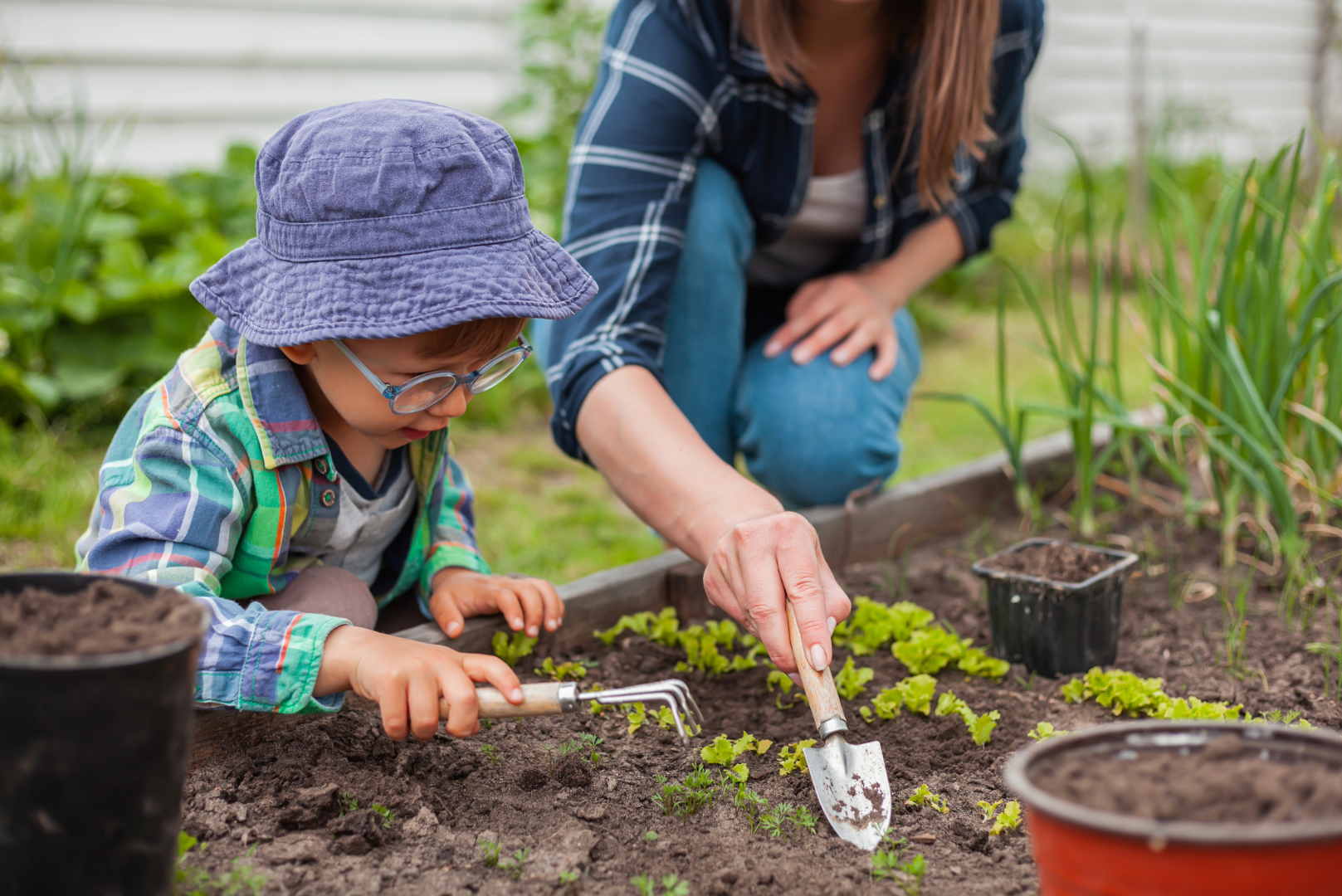 child digging in soil with garden tools
