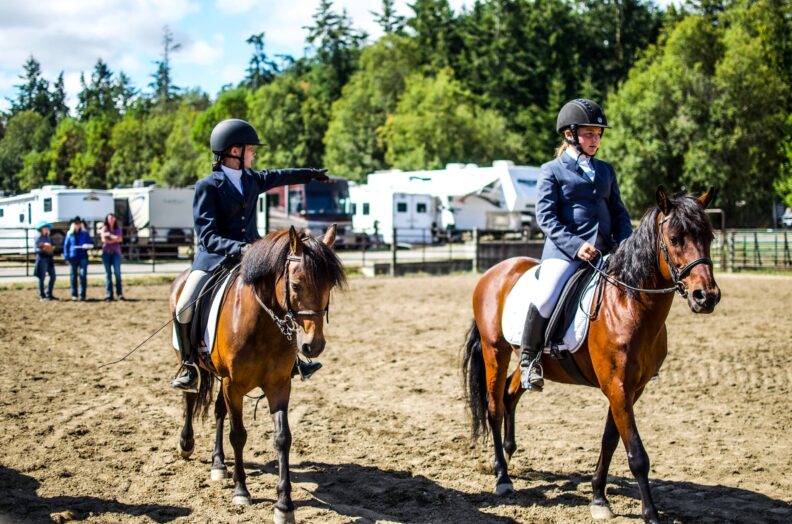 Two young people on horses at fairgrounds