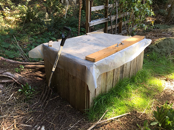 Plastic covers the top of an outdoor wooden box. A handle allows the user to access from the top.