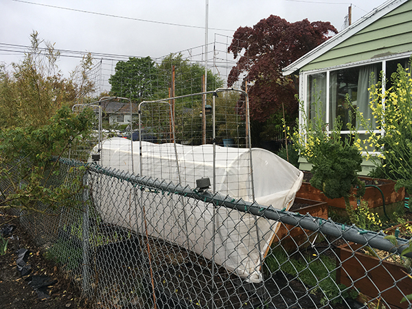 A low tunnel is propped to the side of a garden bed.