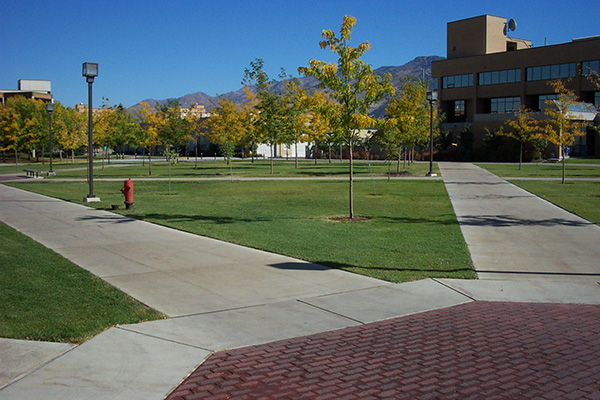 Multiple sidewalks leading from various buildings intersect centrally at a large, open area on a university campus. 