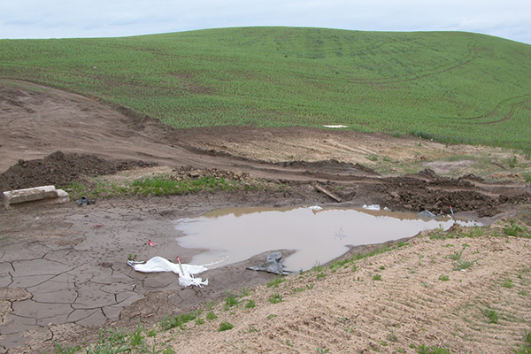 Sediment basin with water pooling at the base of a hill.