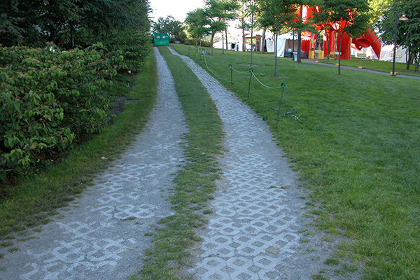 A parallel track of decorative, surface brickwork in parklike setting.