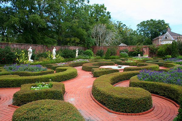 Formal garden with neatly trimmed topiary hedges and brick walkways at Tryon Palace, North Carolina.