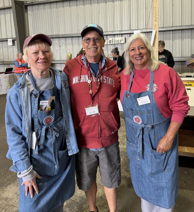 Master Gardeners Diana Sparby, Jack Smith, and Christy Rowe smiling at the camera before the plant sale.