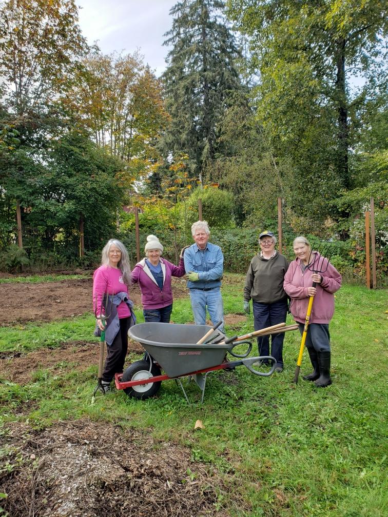 Five volunteers smile and pose in front of newly cleared space for the native plant nursery,