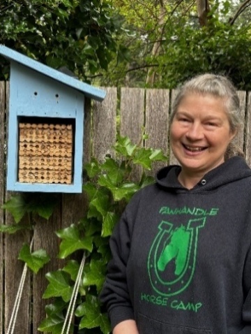 Mason bee fostering participant smiling next to her mason bee house.
