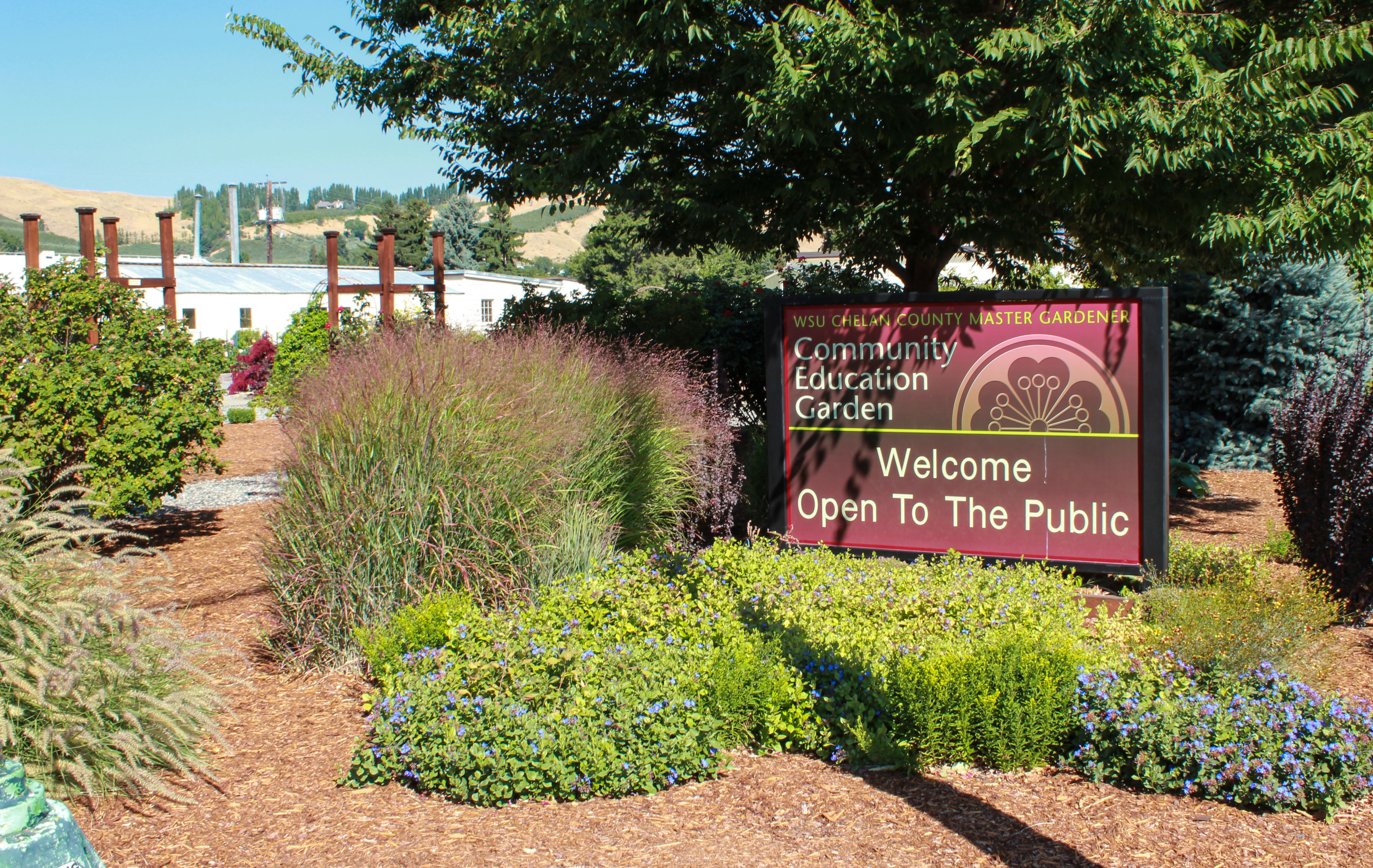 Landscaped entrance to the Community Education Garden with a sign reading ‘Community Education Garden – Welcome, Open to the Public.