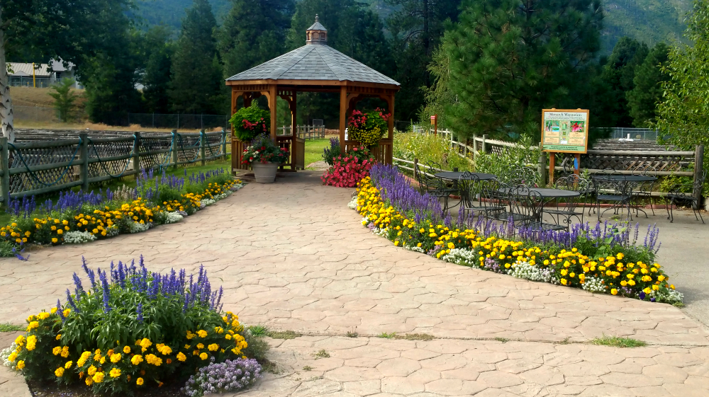 Gazebo with flowers and cement walkway.