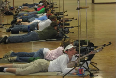 Youth lying down on ground in position to aim rifle