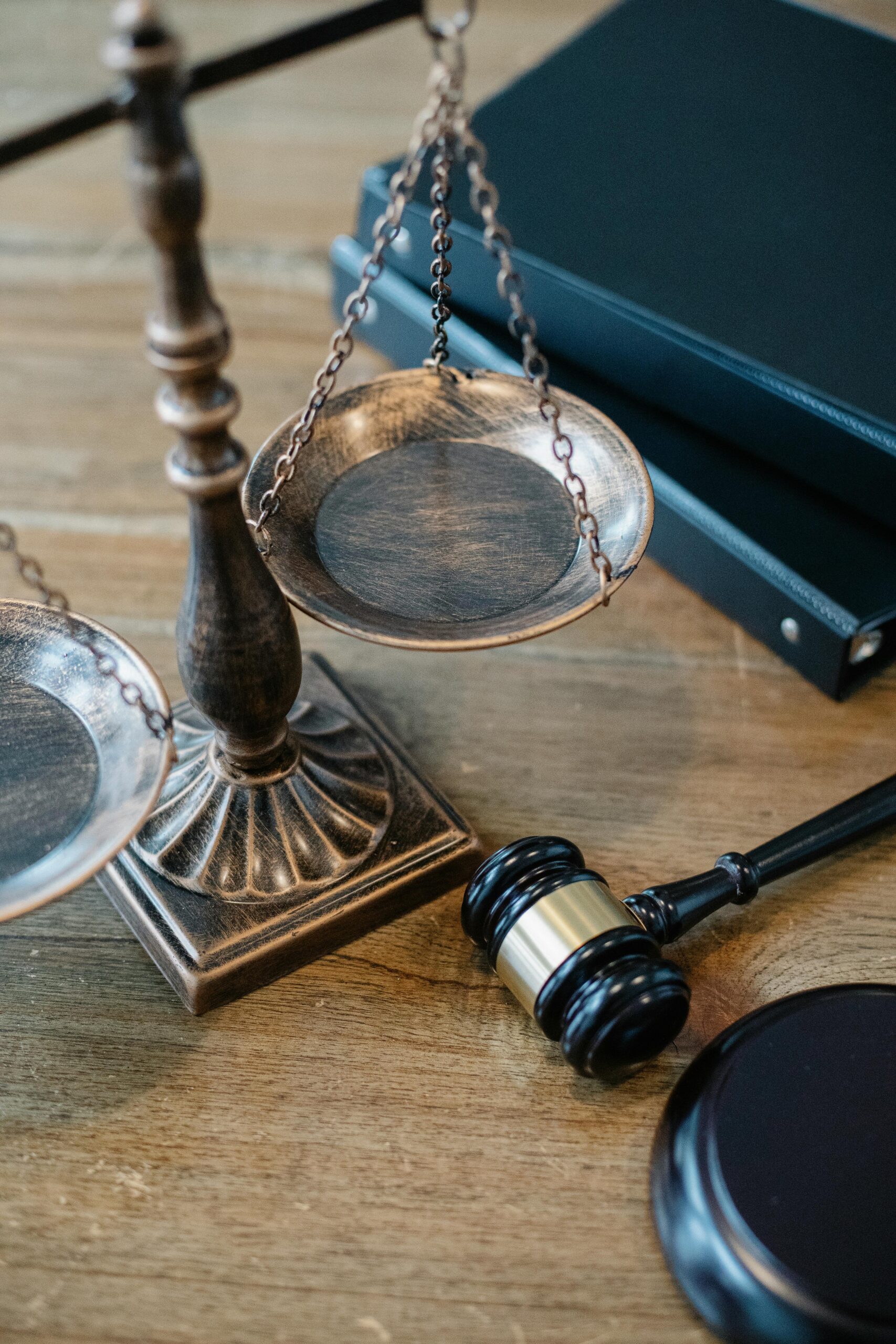 A weighing scale sits on a desk with a gavel and two black folders.