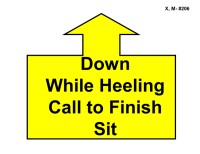 A large yellow arrow outlined in black points straight upward, attached to a wide rectangular base. Inside the base, bold black text reads “Down While Heeling Call to Finish Sit.”
