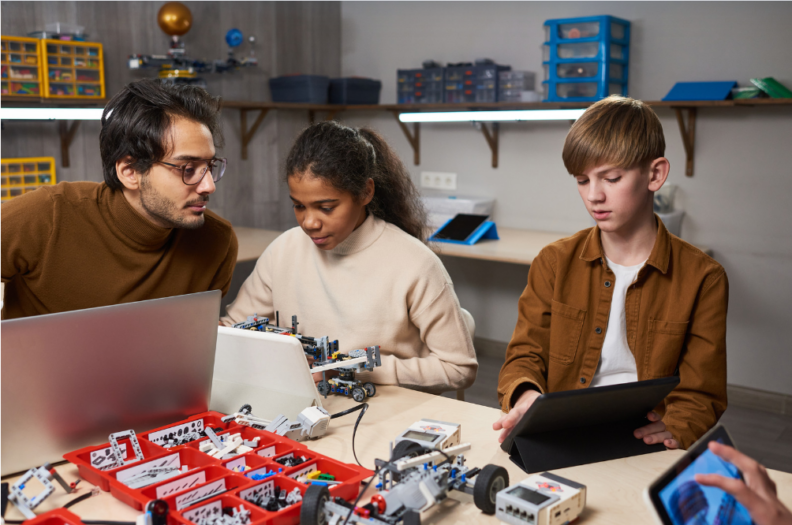Adult mentor with two youth, building robots.