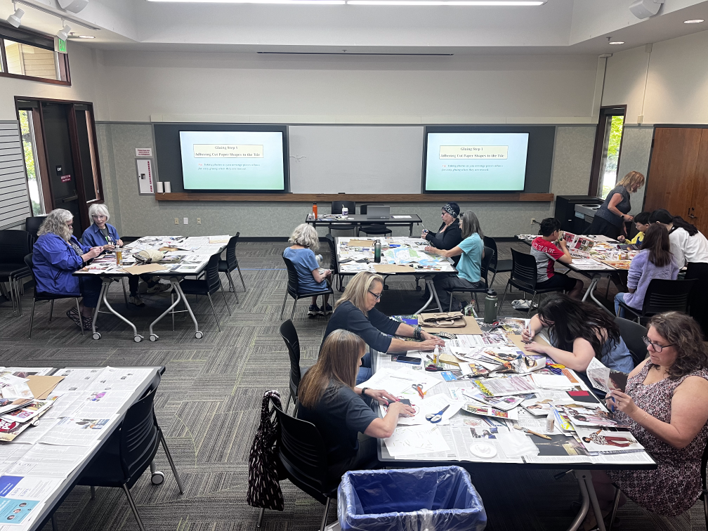 People collaging to make upcycled art while sitting in groups at tables covered in newspaper.