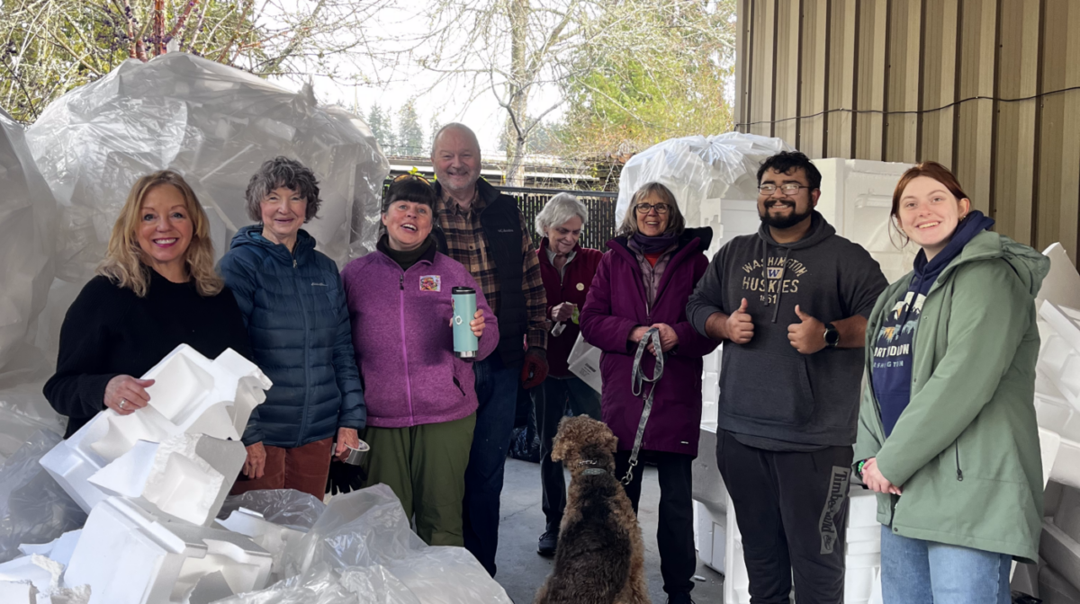 A group of smiling people surrounded by bags of Styrofoam