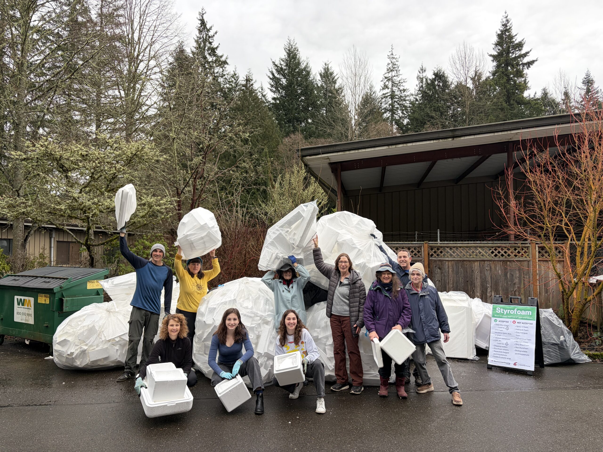 Group photo of volunteers in holding Styrofoam pieces in front of a large pile of Styrofoam.