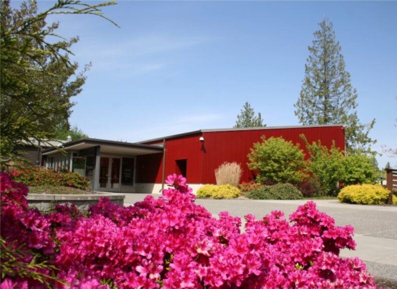 Willis Tucker Park office building is red with covered entrance, glass double doors and large glass windows on either side of the doors.