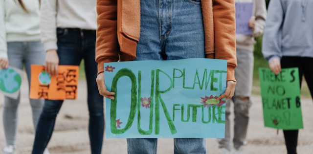 Protesters holding signs with Our Planet Our Future featured