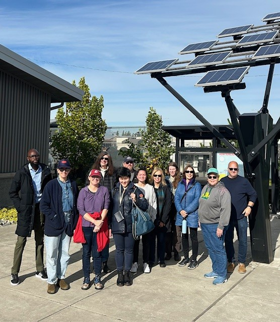 Climate Stewards class of 2025 smiling as a group in front of solar panels in Arlington, WA in Snohomish PUD.