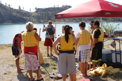 Students standing around leader getting canoeing instructions.