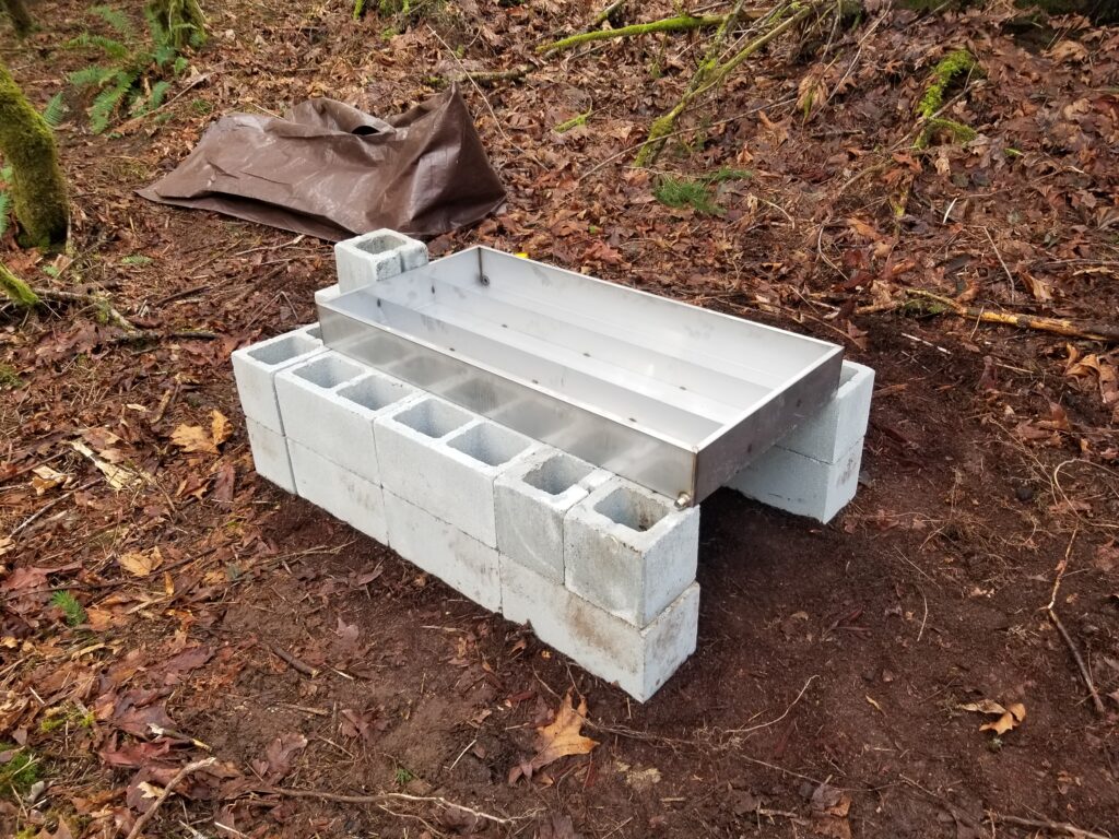 A stainless steel sugaring pan on a cinderblock arch.