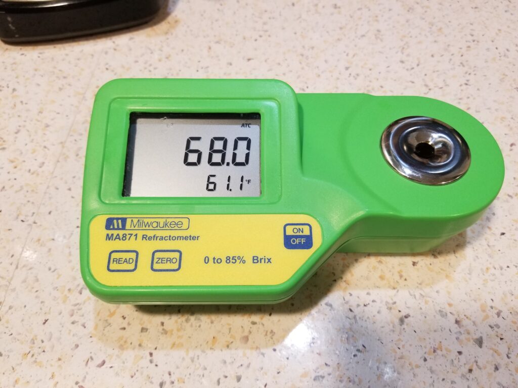 A digital refractometer testing syrup showing 68% brix.